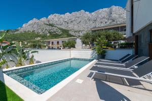 a swimming pool with chairs and mountains in the background at Villa Hillson in Makarska