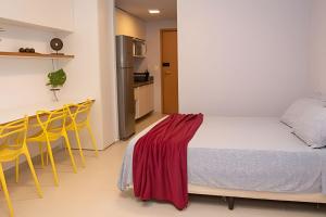Hosts BR - Estúdio Eco Resort Praia dos Carneiros في تامانداري: غرفة نوم بسرير وبعض الكراسي الصفراء