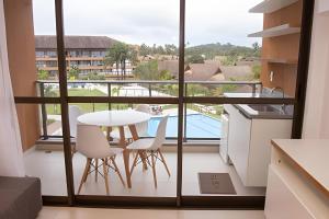 Hosts BR - Estúdio Eco Resort Praia dos Carneiros في تامانداري: غرفة مع شرفة مع طاولة وكراسي