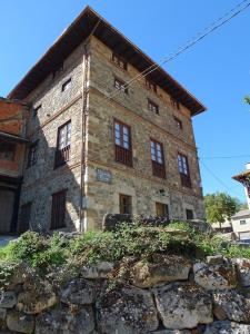 ein altes Steinhaus mit einer Steinmauer in der Unterkunft Casa Rural Sobrevilla II in Pido