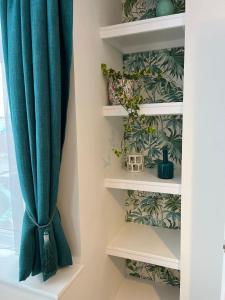 a room with a curtain and shelves with plants at The Rose Marie Lodge in Clacton-on-Sea