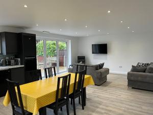 a kitchen and living room with a yellow table and chairs at The Rose Marie Lodge in Clacton-on-Sea