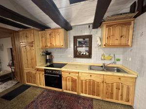 a kitchen with wooden cabinets and a sink at Ferienhaus Historisches Backhäuschen 