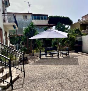 stół piknikowy z parasolką i dwoma ławkami w obiekcie Reversal apartment w mieście Santa Marinella