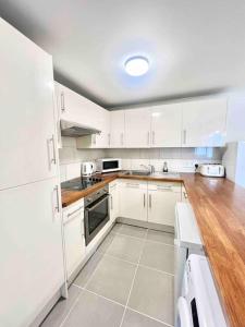 a white kitchen with white cabinets and a wooden floor at LUXstay 2BR Earls Court Apartment Sleeps up to 10 in London
