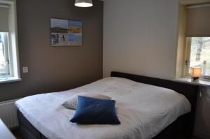 une chambre avec un lit avec un oreiller bleu dessus dans l'établissement Ferienhaus "Wad und Wal" mit Schwimmbad, à Ballum