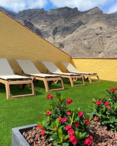 uma fila de mesas de piquenique e flores com montanhas ao fundo em Ferienhaus für 4 Personen und 2 Kinder in Urb La Suerte, Gran Canaria Westküste Gran Canaria em Agaete