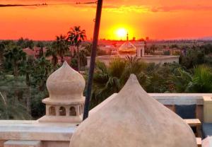 uma vista para o pôr-do-sol a partir da varanda de um edifício em La Perle de l'Atlas by Golf Resort em Marraquexe