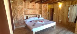 ワタムにあるOcean zuri villaの木製の部屋に白いベッドが備わるベッドルーム1室