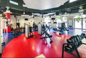 a gym with treadmills and chairs on a red floor at Stylish and Sleek: Modern Well-Furnished One Bedroom Hall and Kitchen Apartment in Dubai