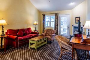 a living room with a red couch and a chair at Cambria Pines Lodge in Cambria