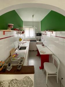 een keuken met groene en witte muren en een tafel bij Casa Serena in Induno Olona