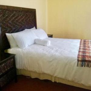 una camera da letto con letto, lenzuola e cuscini bianchi di Letloepe Lodge a Qachaʼs Nek