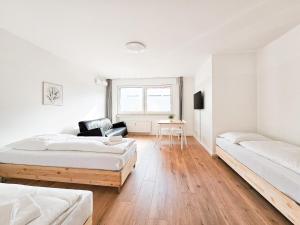 Habitación blanca con 2 camas y silla en RAJ Living - 2 or 3 Room Apartments - 15 Min zur Messe DUS & 10 Min Old Town DUS en Düsseldorf