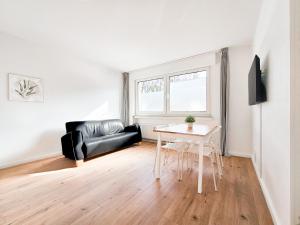 a living room with a black leather couch and a table at RAJ Living - 2 or 3 Room Apartments - 15 Min zur Messe DUS & 10 Min Old Town DUS in Düsseldorf