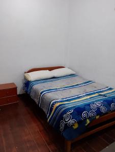 a bed in a room with a white wall at Black Sheep Hostel Cusco in Cusco