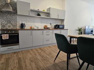 a kitchen with white cabinets and a table with chairs at Stylový byt v srdci Hradce Králové in Hradec Králové