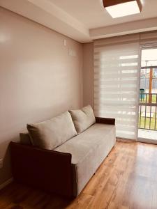 un sofá en una sala de estar con ventana en Apartamento Acqua, 102 A, com vaga de garagem, en Pelotas