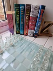 a glass chess board with books on a shelf at Lovely flat located in heart of Lynton. in Lynton
