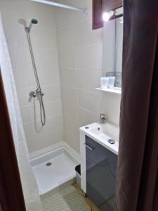 La salle de bains blanche est pourvue d'une douche et d'un lavabo. dans l'établissement Au pied des Remparts 10 rue Saint jean, à Villefranche-de-Conflent