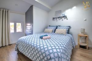 Schlafzimmer mit einem Bett mit einer blauen und weißen Bettdecke in der Unterkunft Charm and Elegance T1 in the heart of Ribérac in Ribérac