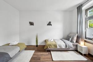 ein weißes Zimmer mit 2 Betten und einem Sofa in der Unterkunft Top Lage Ideal für Geschäftsleute, Monteure, Familien, 3 Zimmer, Flachbild-TV in Wuppertal
