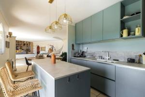 eine Küche mit blauen Schränken und einer Theke mit Stühlen in der Unterkunft Charming provençal family house with swimming pool in Antibes