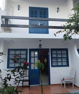 a white house with a blue door and a chair at Casa Azul in Rio das Ostras