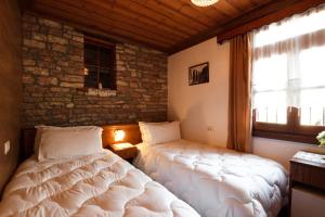 a bedroom with two beds and a brick wall at Hotel Pashai in Gjirokastër