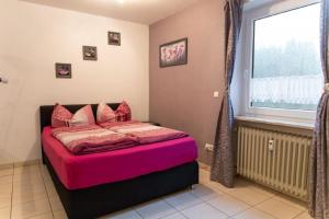 a bedroom with a pink bed with a window at Großzügiges Ferienstudio für zwei Personen in Weißenstadt