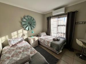 een slaapkamer met 2 bedden en een klok aan de muur bij Die Mossienes in Windhoek