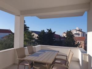 a wooden table and chairs on a balcony at Villa Sunny Day Sendi Deluxe Novalja in Novalja