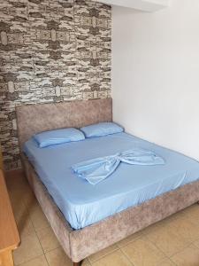 a bed with blue sheets and a brick wall at Hotel Rozafa Velipoje in Baks-Rrjoll