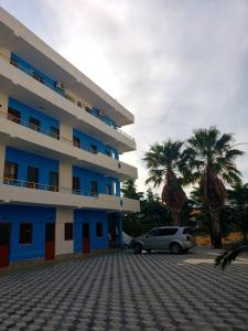 a car parked in front of a building with palm trees at Hotel Rozafa Velipoje in Baks-Rrjoll