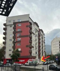 een hoog rood gebouw met auto's geparkeerd op een parkeerplaats bij Apartment 27 in Skopje