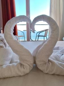 dwa ręczniki w kształcie serc siedzących na łóżku w obiekcie Hotel Cosmos w mieście Eforie Sud