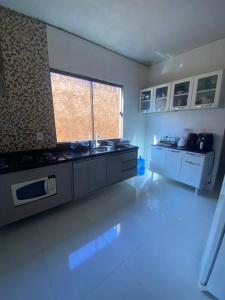 a large kitchen with white counters and a large window at Casa em Luís Eduardo Magalhães in Luis Eduardo Magalhaes