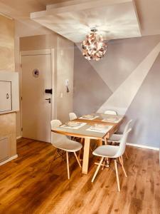 une table à manger avec des chaises blanches et un lustre dans l'établissement Apartamento Acqua, 102 A, com vaga de garagem, à Pelotas