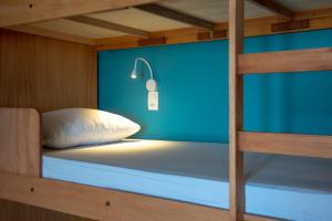 a bunk bed with a white pillow and a blue wall at Longboard Paradise Surf Club in Rio de Janeiro