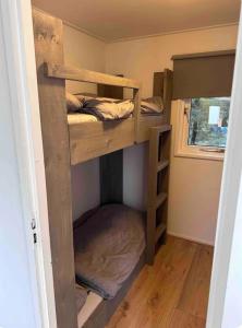 ein Etagenbett in einem winzigen Haus in der Unterkunft Heerlijk chalet midden in de natuur in Putten