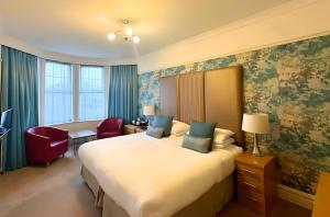 a hotel room with a large bed and a chair at Caerwylan Hotel in Criccieth