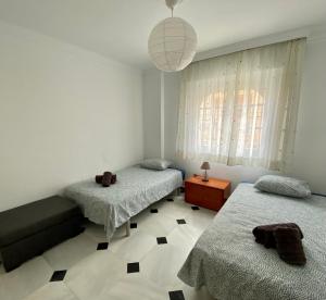 1 dormitorio con 2 camas y luz colgante en En playa, céntrico y acogedor en Fuengirola