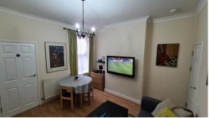 a living room with a table and a tv on the wall at Happy House in Wyken