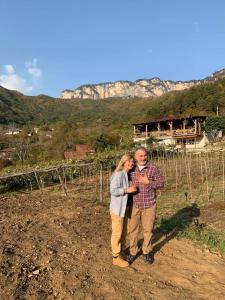 a man and woman standing in front of a vineyard at Korenishuli Veranda Wine Hotel in Tsʼageri