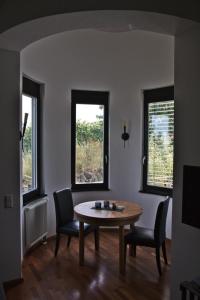a dining room with a table and two windows at Schöne Ferienwohnung in Sasbach Am Kaiserstuhl mit Grill und Terrasse in Sasbach am Kaiserstuhl
