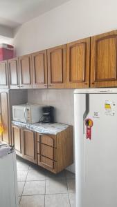 - une cuisine avec des placards en bois et un réfrigérateur blanc dans l'établissement Vila Mirim - Mendes House, à Praia Grande
