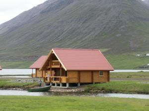 a cabin on the water with a mountain in the background at Brimnes Bungalows in Ólafsfjörður