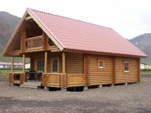 a large log cabin with a red roof at Brimnes Bungalows in Ólafsfjörður