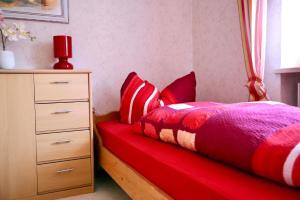 a bedroom with a red bed and a dresser at Große Wohnung in Weißenstadt in Weißenstadt