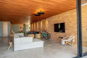 - un salon avec un canapé et une télévision sur un mur en briques dans l'établissement Anaya - Villas de Luxo, à Passo de Camarajibe